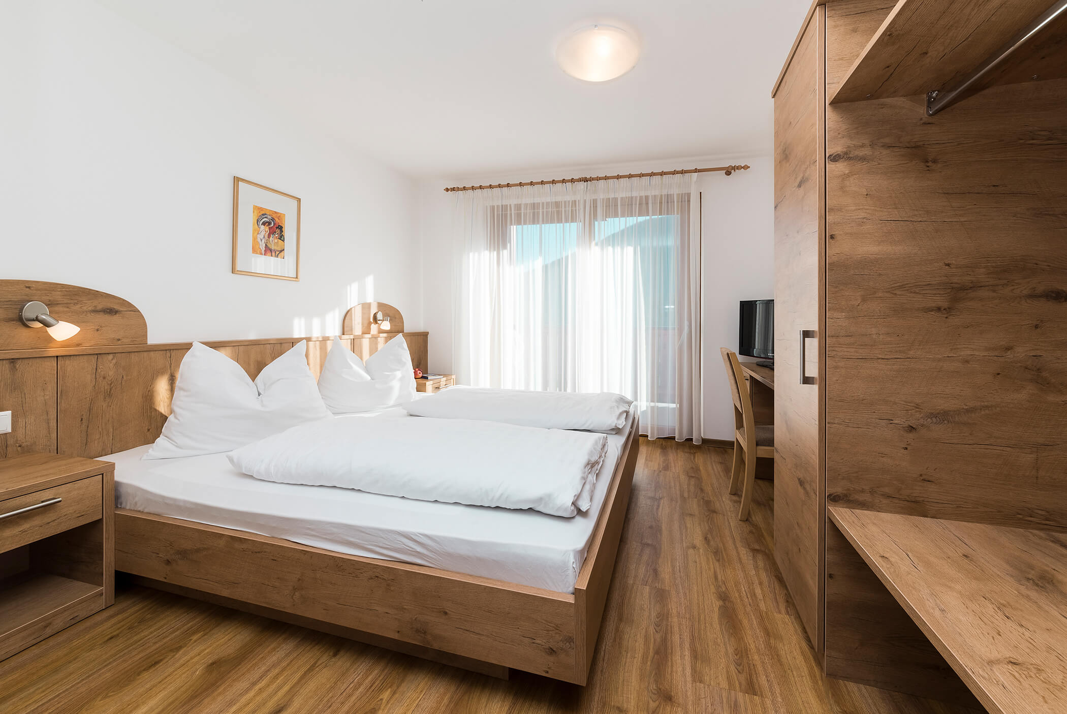 Modernes Schlafzimmer mit Doppelbett, Kleiderschrank und Blick auf den Balkon - Schirmerhof
