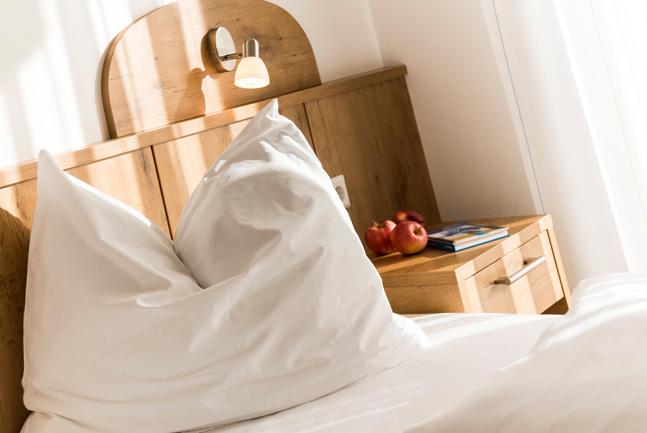 Freshly made up bed with bedside table and apple basket - Schirmerhof