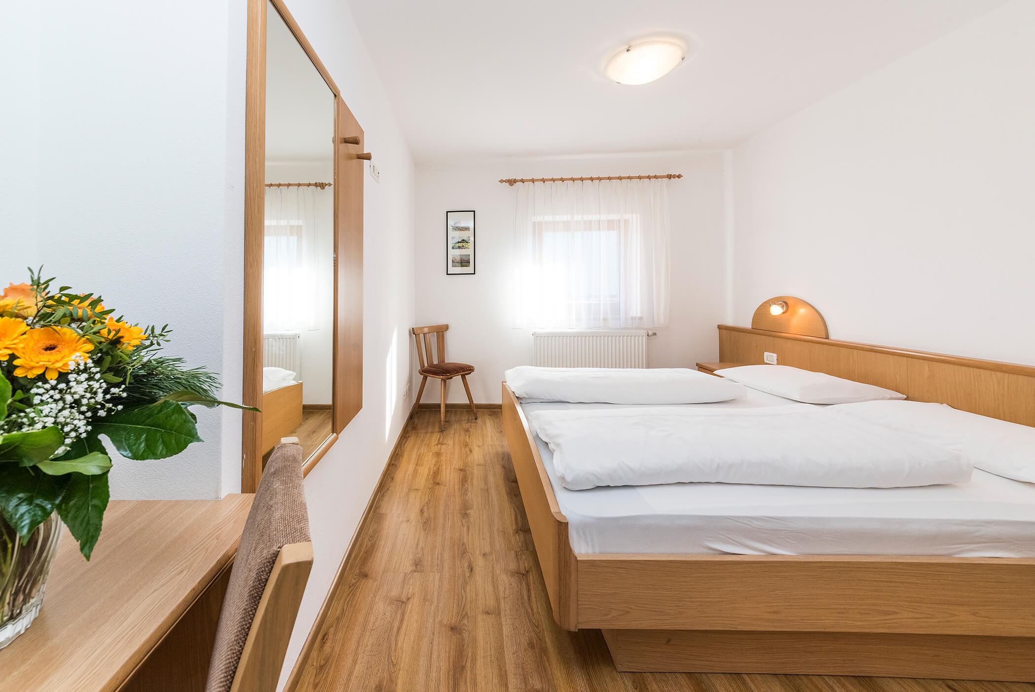 Bright bedroom with large double bed and mirror - Schirmerhof