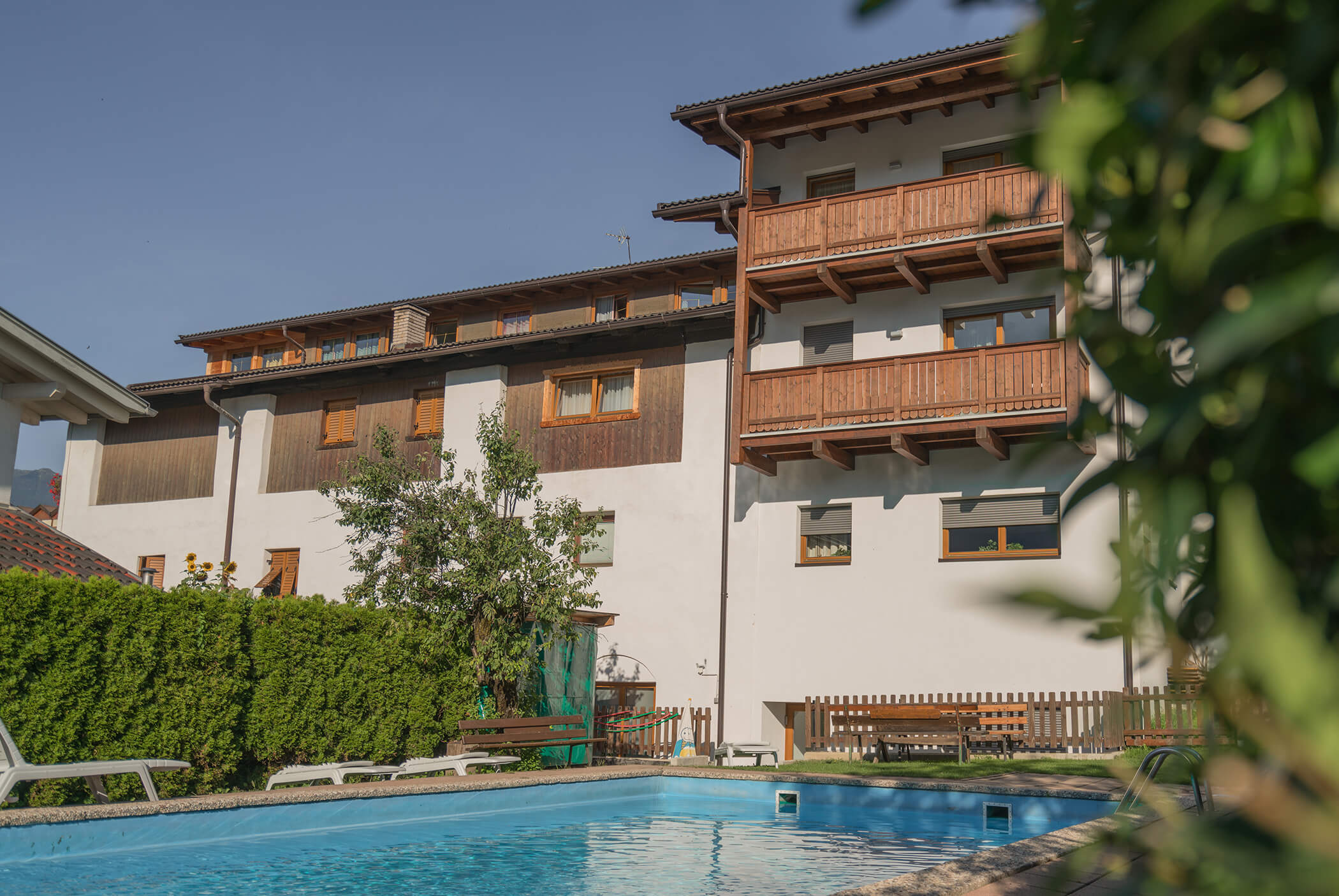 Der Außenpool mit Sonnenliegen und Blick auf den Schirmerhof