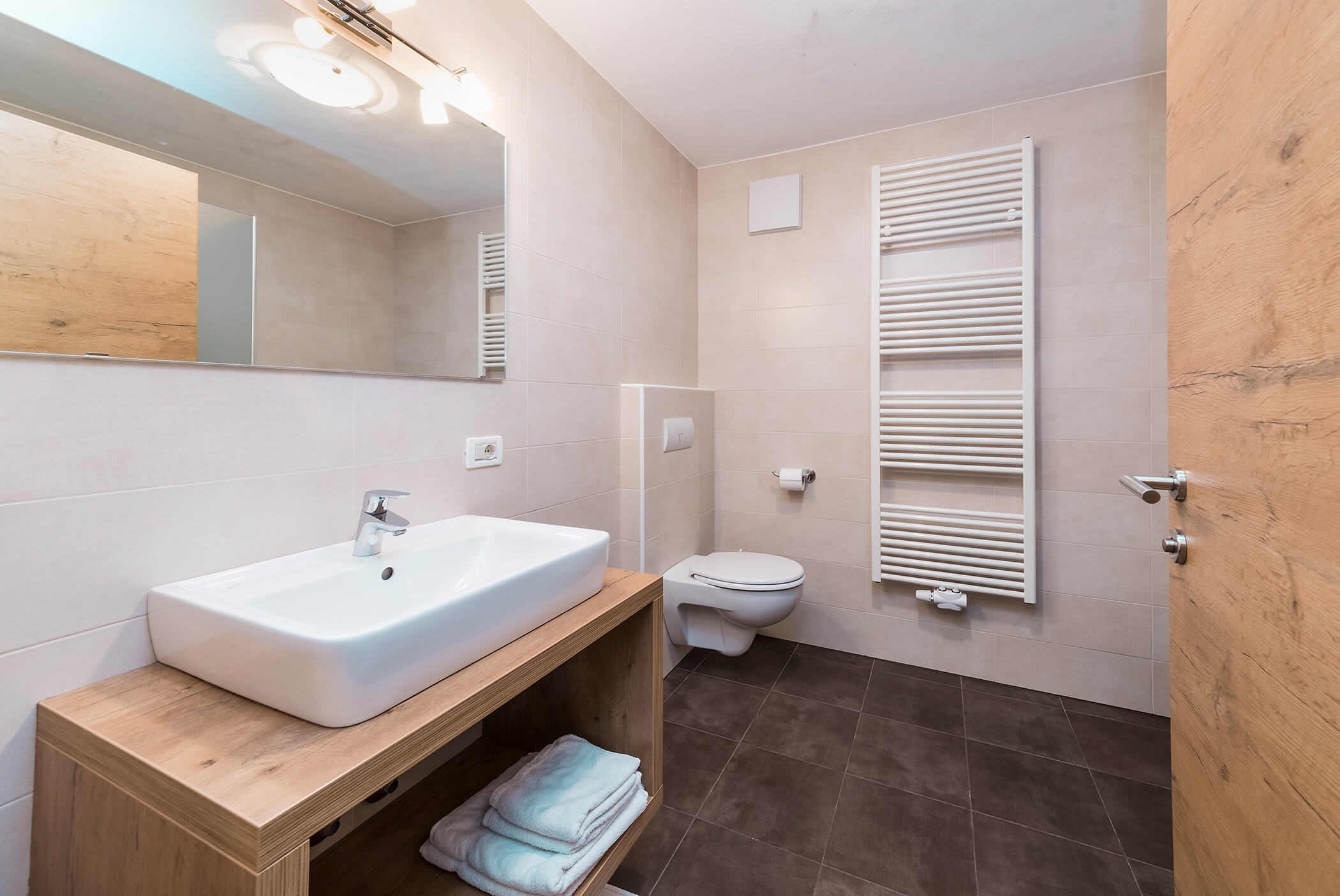 Bathroom with washbasin, large mirror and toilet - Schirmerhof